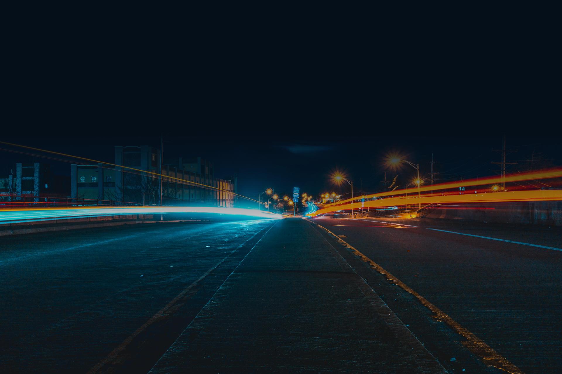 Time lapse photo of car lights on a dark road